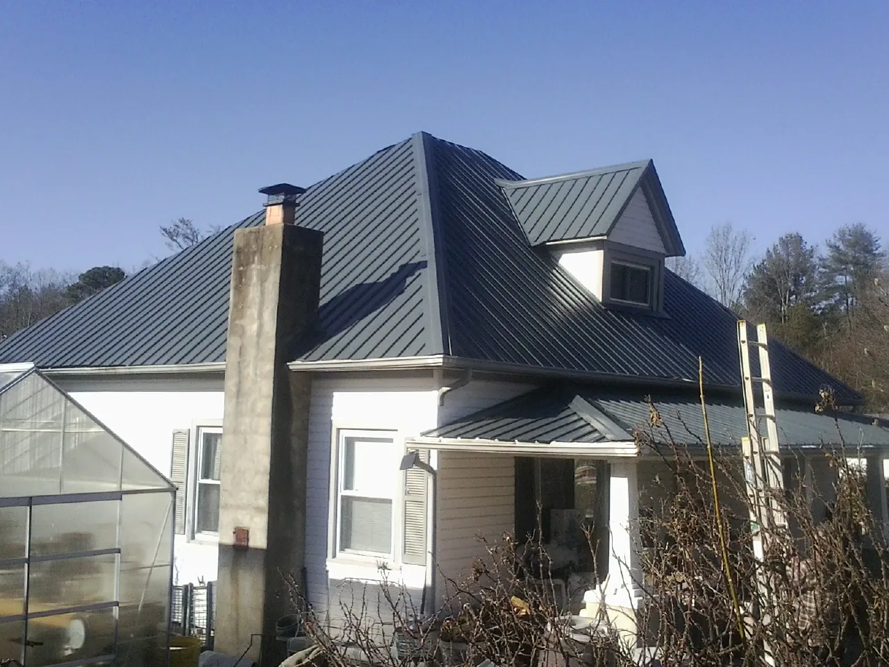 Dark blue standing seam metal roof on a white farmhouse with dormer — Slate & Tile Roof Repair by Roofing Brothers in Millstone Township
