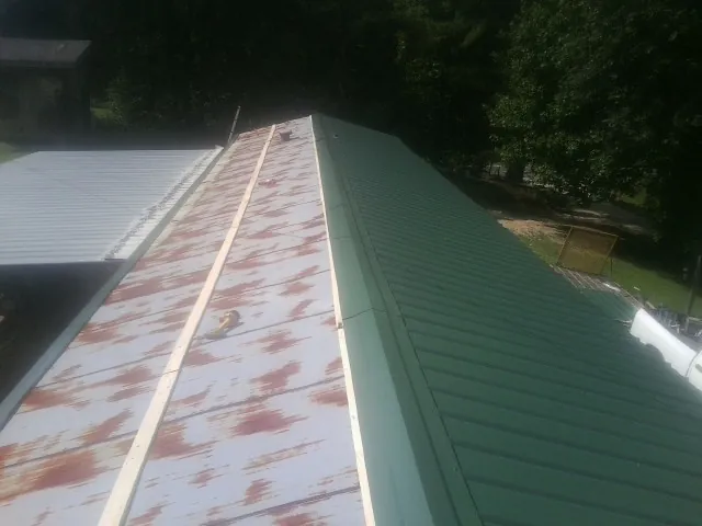Old rusted panels beside newly installed green metal roofing — Wind Damage Roof Repair by Roofing Brothers in Millstone Township