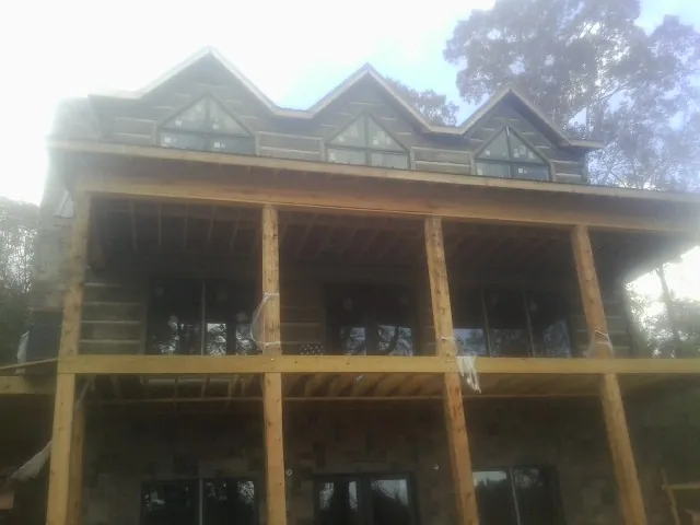 Dormers and porch framing on a large log home under construction — Roof Coating work by our crew in Millstone Township
