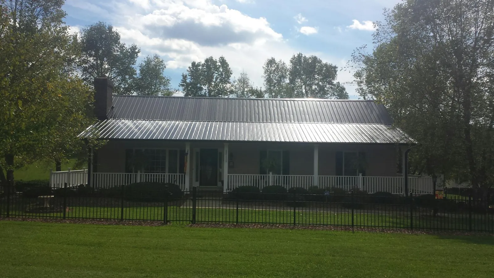 Gray metal roof on a brick ranch with a full width front porch — Gutter Guard Installation work by our crew in Millstone Township