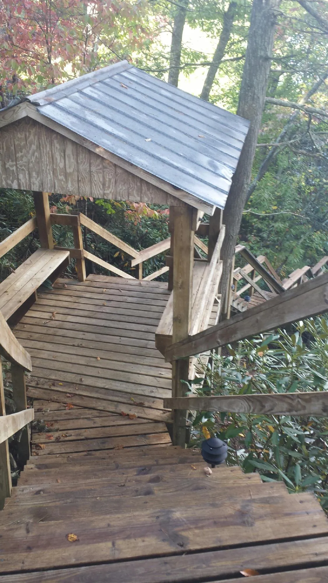 Metal roofed shelter over wooden steps on a wooded walkway — Skylight Repair & Installation work by our crew in Millstone Township