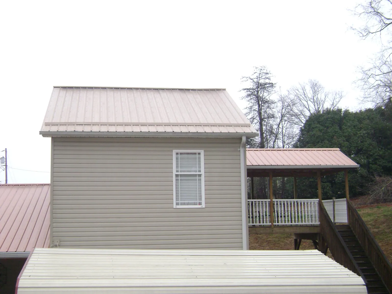 Tan metal roofs on a two story addition and attached porch, from a Roof Replacement job in Millstone Township