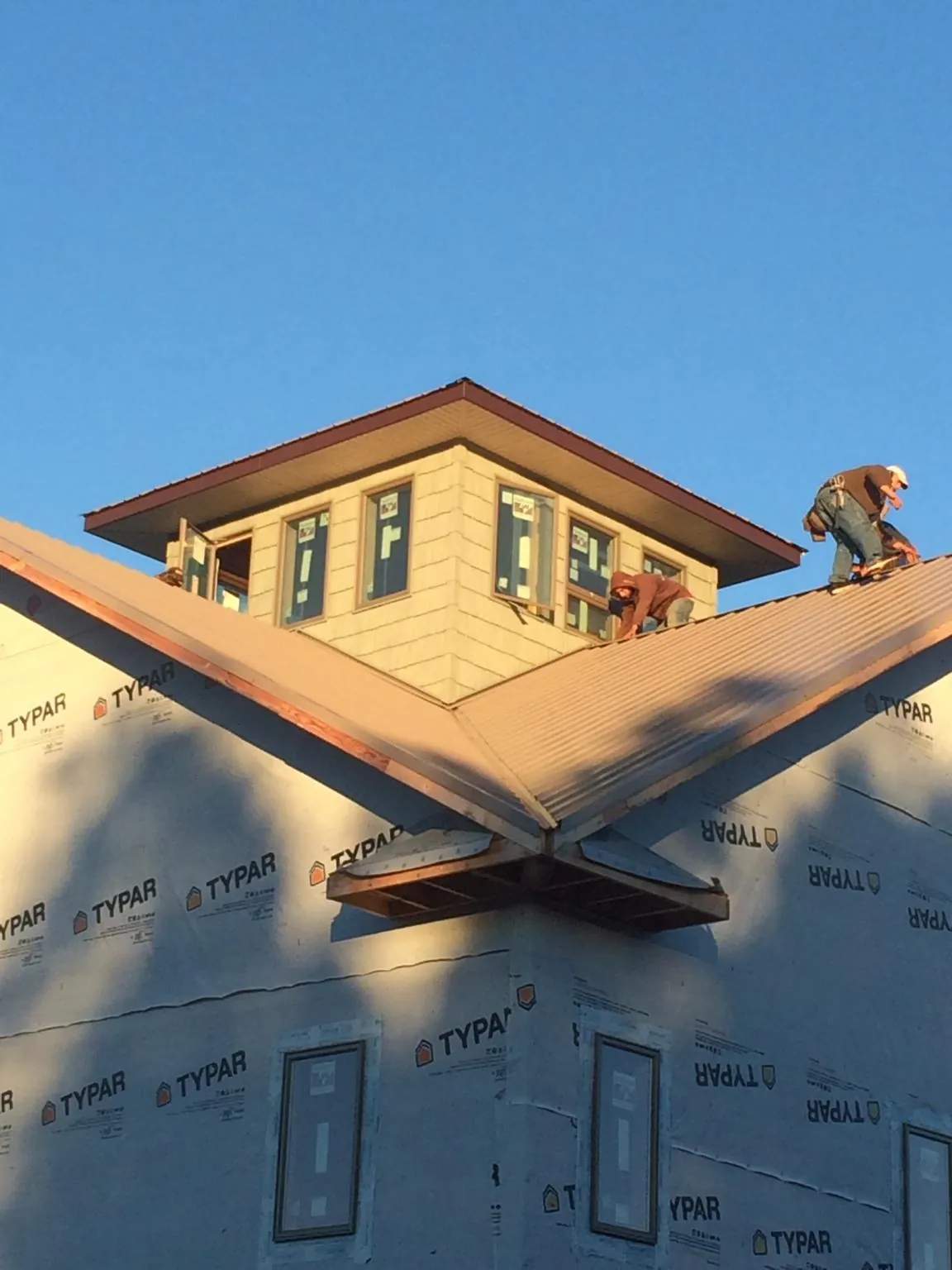 Roofers working around a rooftop cupola on a new metal roof at sunset — Roof Waterproofing in Millstone Township by Roofing Brothers